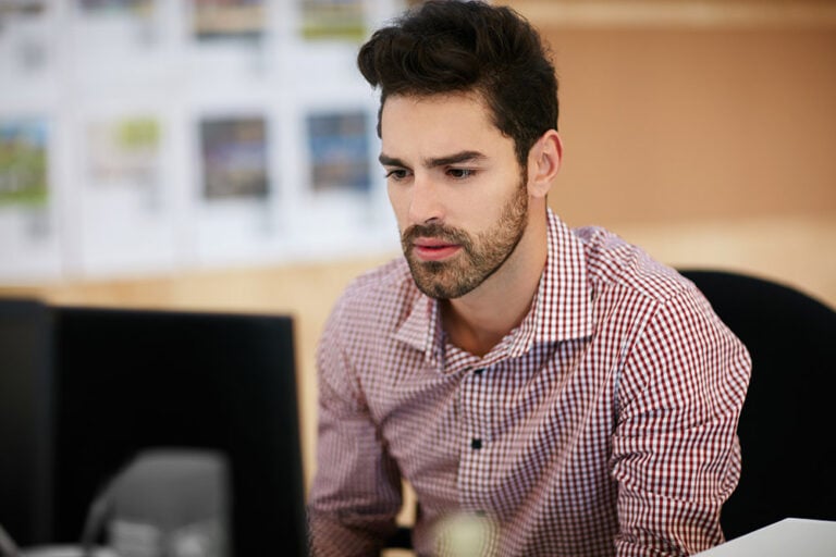 Man at his desk looking at a computer monitor