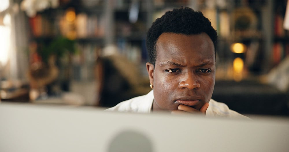 Man working at a computer with a slightly skeptical look on his face
